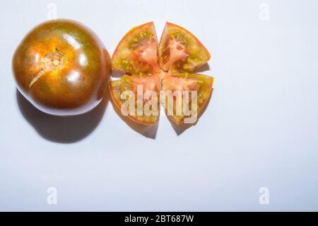 Une paire de tomates fraîches de Kumato ouvre en deux et hachée sur fond blanc Banque D'Images