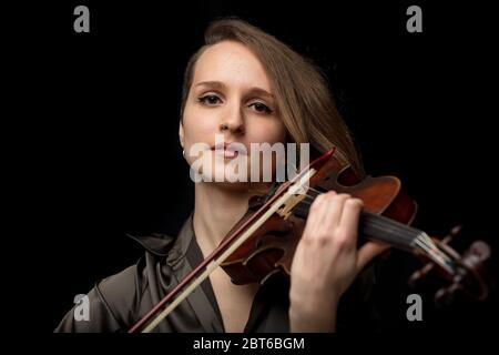 Jeune violoniste ou musicienne sérieuse jouant sur un violon baroque antique lors d'une performance de musique classique dans une tête et des épaules p frontal Banque D'Images