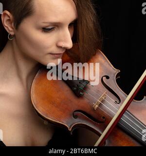 Femme au nez percé jouant un violon classique lors d'une représentation en direct ou d'un récital en gros plan sur son visage et son instrument Banque D'Images