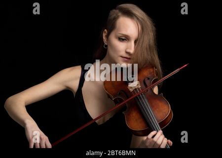 Violoniste moderne et tendance jouant sur un violon baroque antique fait à la main dans un concert de musique classique ou un récital sur fond noir Banque D'Images