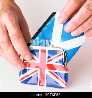 Les mains forcent un gros sac à main écossais dans un petit sac à main drapeau de l'Union Banque D'Images