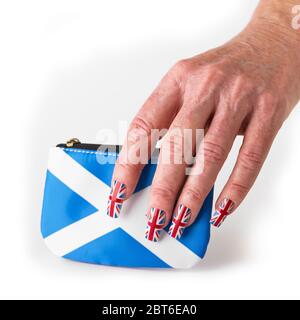 Main portant drapeau Union faux ongles tenant Scottish Saltyre sac à main sur fond blanc Banque D'Images