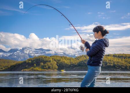 Pêche à la femme sur la canne à pêche spinning en Norvège. La pêche en Norvège est une façon d'embrasser le mode de vie local. D'innombrables lacs et rivières et d'une ampleur Banque D'Images