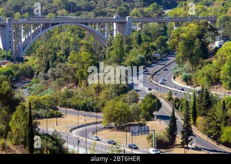 Pont avec arche et route asphaltée qui coupe un chemin à travers la forêt, Banque D'Images