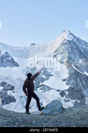 Vue latérale instantané d'un touriste pointant sur l'une des plus belles montagnes des Alpes suisses - Ober Gabelhorn, dont un côté est couvert de neige. Nature avec vue imprenable. Tourisme sportif dans les Alpes. Banque D'Images