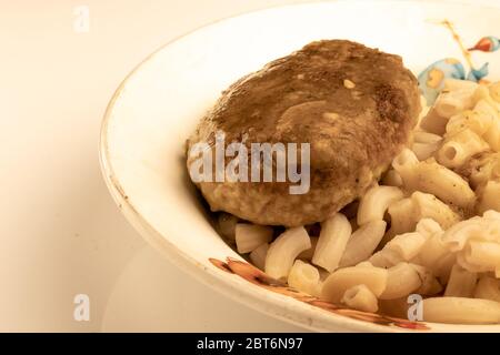 Une assiette de pâtes et un gros plan de boulettes de viande sur une table blanche. Banque D'Images