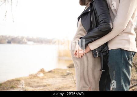 Un gars et une fille enceinte embrassent leur ventre. Grossesse et maternité. Banque D'Images