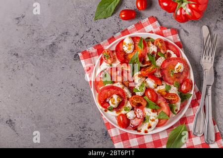 Salade de caprese italienne avec tomates en tranches, mozzarella, basilic, huile d'olive, vinaigre balsamique. Vue de dessus, espace de copie. Banque D'Images