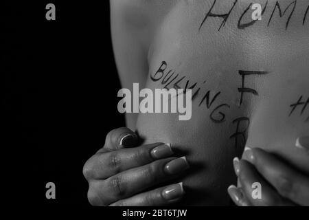 partie du corps d'une jeune fille avec l'inscription humiliation, haine, liberté. les inscriptions sont écrites par la main du photographe, pas un tatouage Banque D'Images