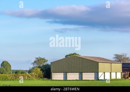 Construction de ferme préfabriquée dans un cadre rural par une journée ensoleillée avec ciel bleu. Banque D'Images