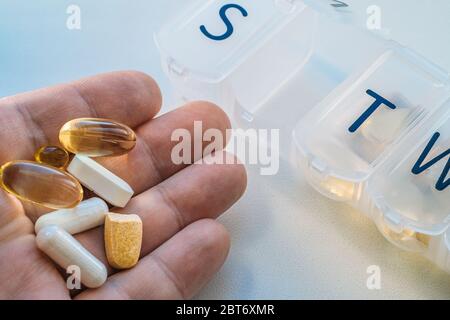 Les hommes montrent sur la paume de la main la portion quotidienne des vitamines, médicaments, comprimés, suppléments alimentaires, gros plan, tonicité Banque D'Images