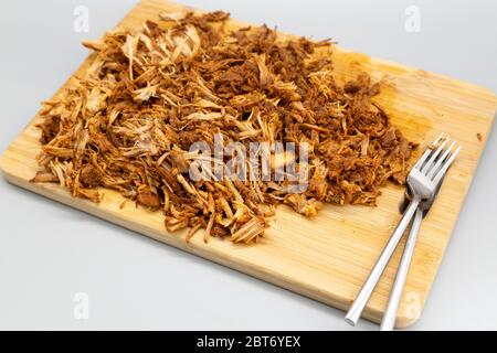 Porc tiraillé à la maison servi râpé sur un panneau de bois. Le plat a été préparé dans une cuisinière lente et cuit pendant neuf heures. Banque D'Images