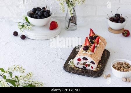 Rouleau de meringue avec baies de pralines à la pistache fraîches et crème fouettée et crème au fromage caillé. Dessert d'été Banque D'Images