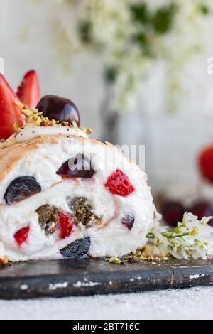 Rouleau de meringue avec baies de pralines à la pistache fraîches et crème fouettée et crème au fromage caillé. Dessert d'été Banque D'Images