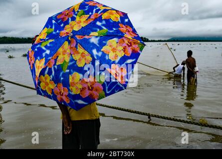 Guwahati, Assam, Inde. 23 mai 2020. Un garçon sous un parapluie sur la rive de la rivière Brahmaputra dans le fond de nuages sombres couvrant le ciel pendant une journée de pluie, à Guwahati. Crédit : David Talukdar/ZUMA Wire/Alay Live News Banque D'Images