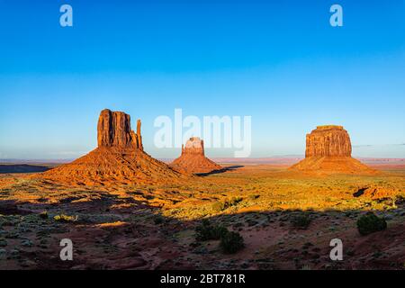 Vue panoramique sur les célèbres buttes et l'horizon de Monument Valley au coucher du soleil lumière colorée et vibrante de l'Arizona avec des rochers orange Banque D'Images