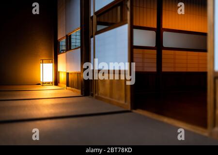 Chambre japonaise traditionnelle vue à angle bas dans la maison ou ryokan avec shoji ouvert portes coulissantes en papier tatami sol et lampe illuminée la nuit sans Banque D'Images