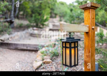 Le soir, au Japon, avec une lampe de lanterne suspendue éclairée sur poteau en bois dans le jardin japonais avec marches et arbres verts en forme de feuillage Banque D'Images