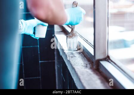 Mains en gants peignant un mur blanc Banque D'Images