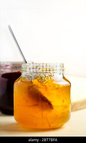 marmelade d'orange maison cueillant la confiture dans un pot en verre, petit déjeuner sucré sur fond de bois clair avec espace pour les copies Banque D'Images