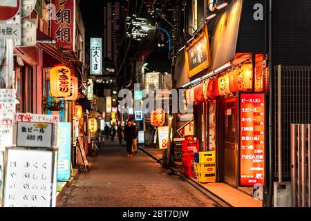 Tokyo, Japon - 3 avril 2019 : quartier Shinjuku au centre-ville avec une ruelle étroite rue avec des restaurants izakaya la nuit et des panneaux près de la gare d'Okubo Banque D'Images