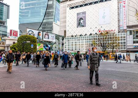 Tokyo, Japon - 28 mars 2019 : célèbre traversée de Shibuya dans le centre-ville avec de nombreuses personnes marchant portant un masque pendant la journée vue sur la ville Banque D'Images