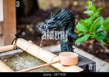 Tokyo, Japon - 30 mars 2019 : entrée du sanctuaire HIE avec fontaine de purification d'eau courante avec jardin japonais vert et louche de bambou Banque D'Images