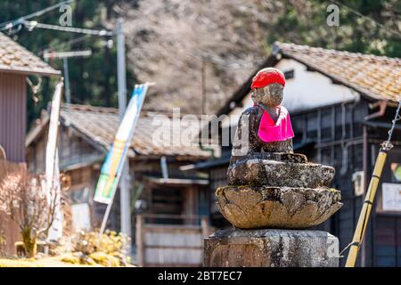 Nikko, Japon - 5 avril 2019 : clôture de la statue de Jizo de bavoir rouge à Kanmangafuchi Abyss, Nikko, Tochigi au Japon, protégeant les morts avec des maisons de bâtiments Banque D'Images