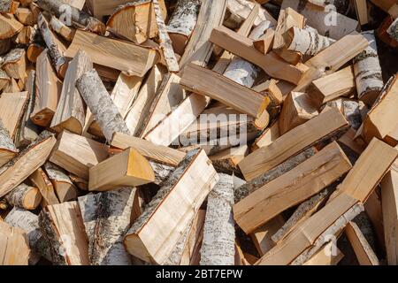 Fond de bois de chauffage haché. Stock de bois pour le chauffage de poêle pour l'hiver. Bûches de bouleau ébréchées dans un gros tas Banque D'Images