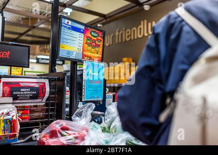 Herndon, USA - 17 avril 2020 : une femme se tenant trop près de la caisse enregistreuse dans le marché alimentaire de l'épicerie Lotte avec un signe pour la distanciation sociale de Banque D'Images