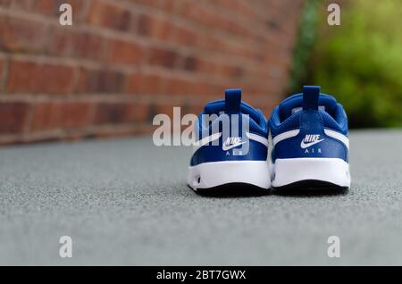 Photo en gros plan de la paire de baskets Nike Air bleues pour enfant sur l'herbe verte vibrante. Le champ de vision peu profond a été utilisé pour l'imagerie. Banque D'Images