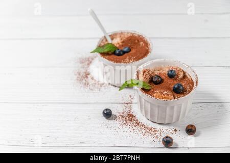 Dessert tiramisu classique avec bleuets, menthe dans un pot blanc sur fond gris Banque D'Images