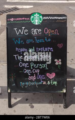 Un panneau de trottoir devant un Starbucks indique qu'il est ouvert et qu'il est accompagné de citations et de gribouillages inspirants pendant la pandémie du coronavirus ou du covid-19 Banque D'Images