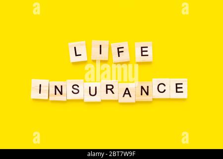assurance vie de mots. Blocs en bois avec lettrage sur fond jaune. Concepts d'assurance Banque D'Images