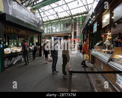 Londres. ROYAUME-UNI. Le 23 mai 2020 à midi. Vue des gens qui font la queue et font du shopping dans un poissonnier au marché de Borough pendant l'épidémie. Banque D'Images