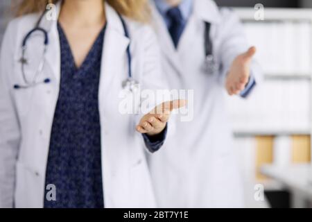 Deux médecins debout et offrant une main d'aide pour secouer la main ou sauver la vie. Aide médicale, lutte contre l'infection virale et le concept de médecine Banque D'Images
