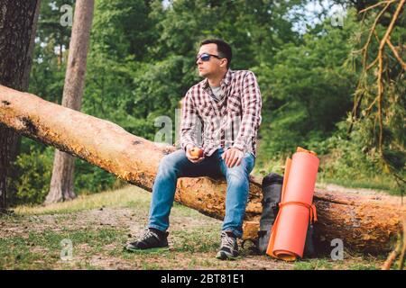 Le thème est une saine alimentation et le végétarisme. Activités de plein air dans la forêt et encas aux fruits. Jeune homme de race caucasien se reposant et mangeant un Banque D'Images