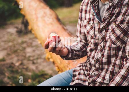 Le thème est une saine alimentation et le végétarisme. Activités de plein air dans la forêt et encas aux fruits. Jeune homme de race caucasien se reposant et mangeant un Banque D'Images