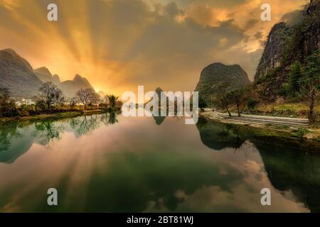 Vue spectaculaire du soleil se levant derrière les montagnes karstiques en calcaire dans le comté de Yangshuo avec la scène reflétée dans la rivière Banque D'Images