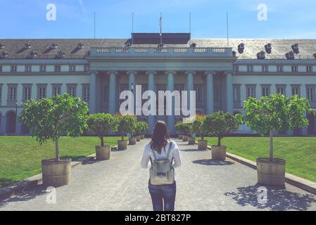 Une femme touristique se trouve dans les jardins verdoyants, en face de l'entrée principale d'un beau château Banque D'Images