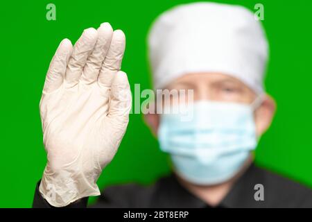 Médecin homme en chirurgie masque facial sur le premier plan de flou artistique a mis la paume de sa main en protection latex gant premier plan, vagues par sa main Banque D'Images