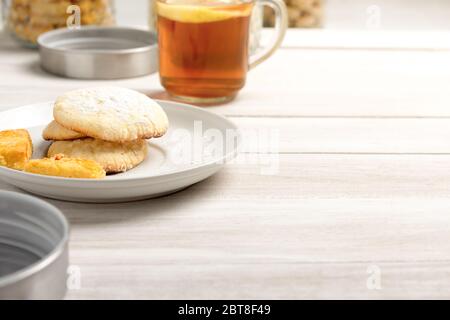 Image de concept alimentaire avec biscuits au beurre de citron et un verre de thé de citron sur table blanche rustique avec espace pour le texte. Banque D'Images