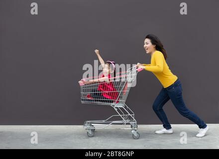 bonne maman et enfant vont faire le panier ensemble. Action drôle de la mère et de l'enfant aller au commerce moderne ou centre commercial avec le chariot Banque D'Images