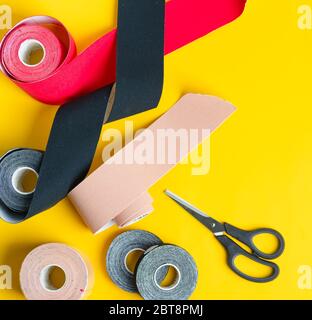 Kit pour kinésiologie traitement de bande de physio spécial rouleaux de différentes couleurs et ciseaux pour couper sur un fond jaune, espace de copie Banque D'Images