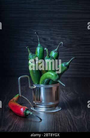 Sur une table en bois dans un porte-gobelet en métal sont des poivrons chauds verts Banque D'Images