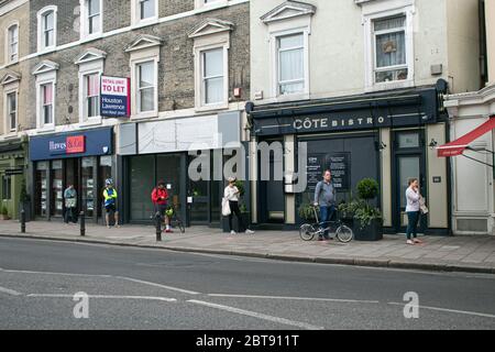 WIMBLEDON LONDRES, ROYAUME-UNI. 24 mai 2020. Les gens ont pris des distances et maintiennent la distance de 2 mètres pour arrêter la propagation du coronavirus Covid-19 comme l'attente dans la file d'attente devant un café sur Wimbledon High Street. Crédit : amer ghazzal/Alay Live News Banque D'Images