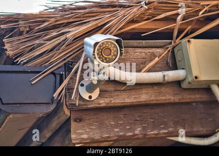 Cette photo unique montre une caméra cachée sous un toit en chaume pour surveiller la zone et assurer la sécurité Banque D'Images