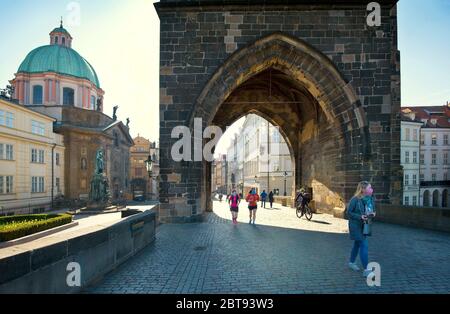 Prague, République tchèque. Personnes sur le pont Charles, la tour du pont de la vieille ville et la statue de l'empereur Charles IV dans l'arrière-pays du soleil du matin. Mai 2020 Banque D'Images