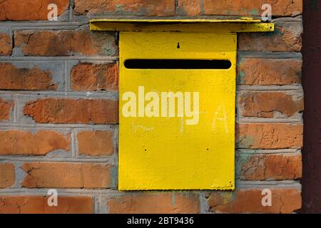 Boîte aux lettres personnelle Old Metal jaune dans un mur de briques rouges. Boîte pour la réception de lettres et autres courriers papier. Trou dans le tiroir pour recevoir la correspondance Banque D'Images