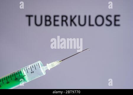 Cette photo montre une seringue jetable avec aiguille hypodermique, TUBERKULOSE écrit sur un tableau gris derrière Banque D'Images